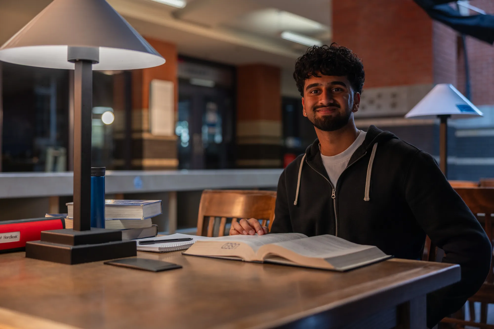 Young man studying with an open book at a library desk