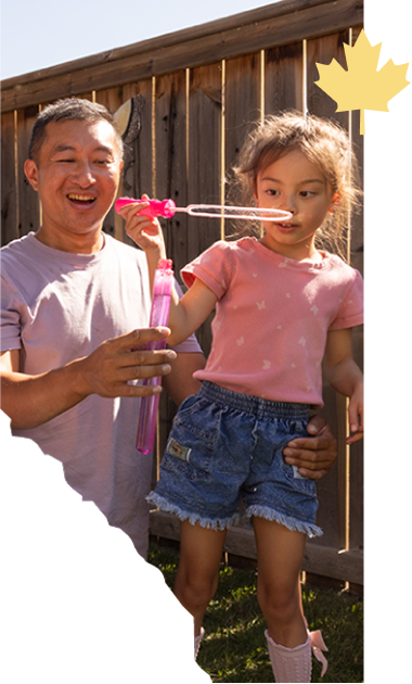 Father and young daughter blowing bubbles together in a backyard
